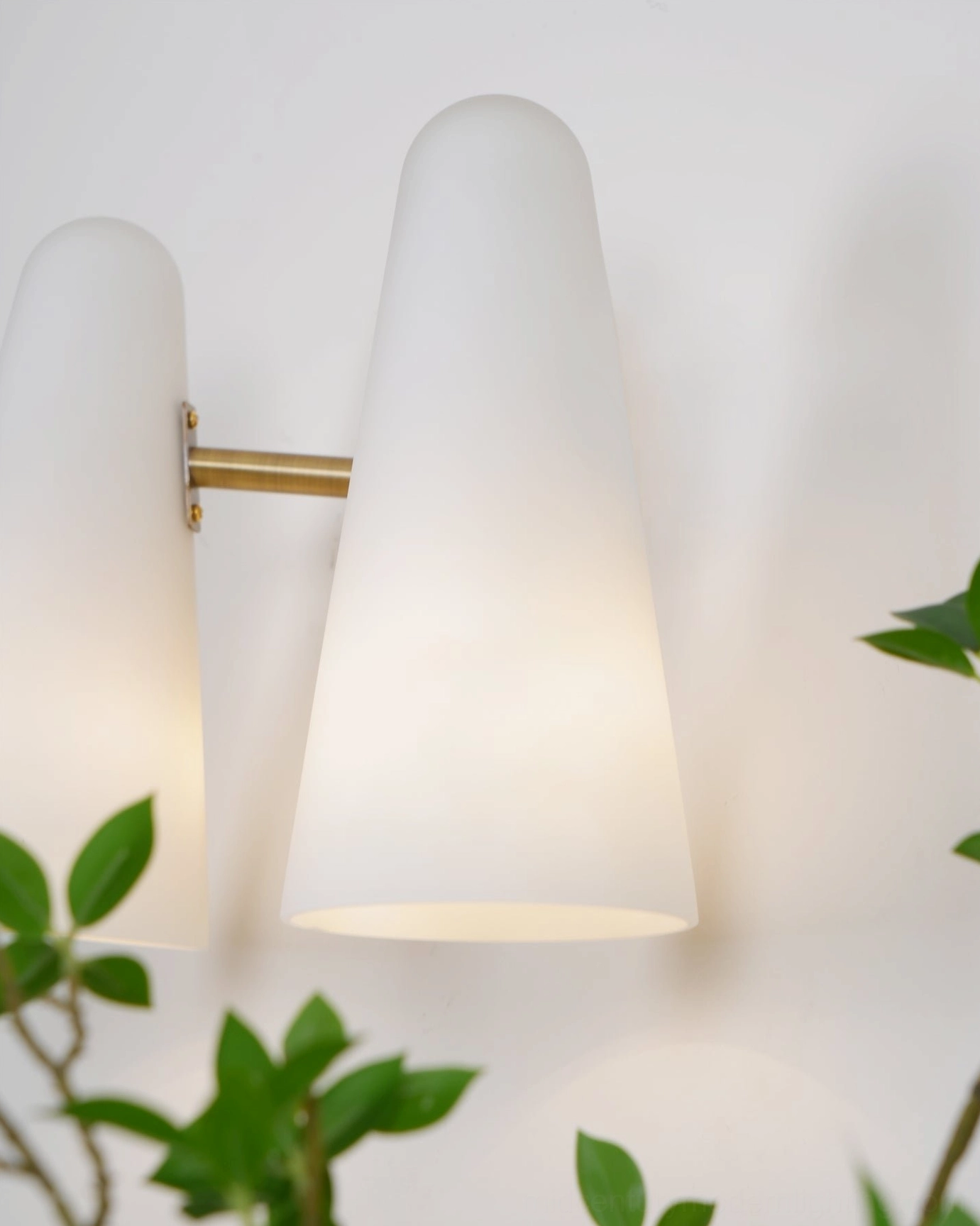 Montfaucon cone sconce close-up showing polished brass hardware and frosted white glass construction