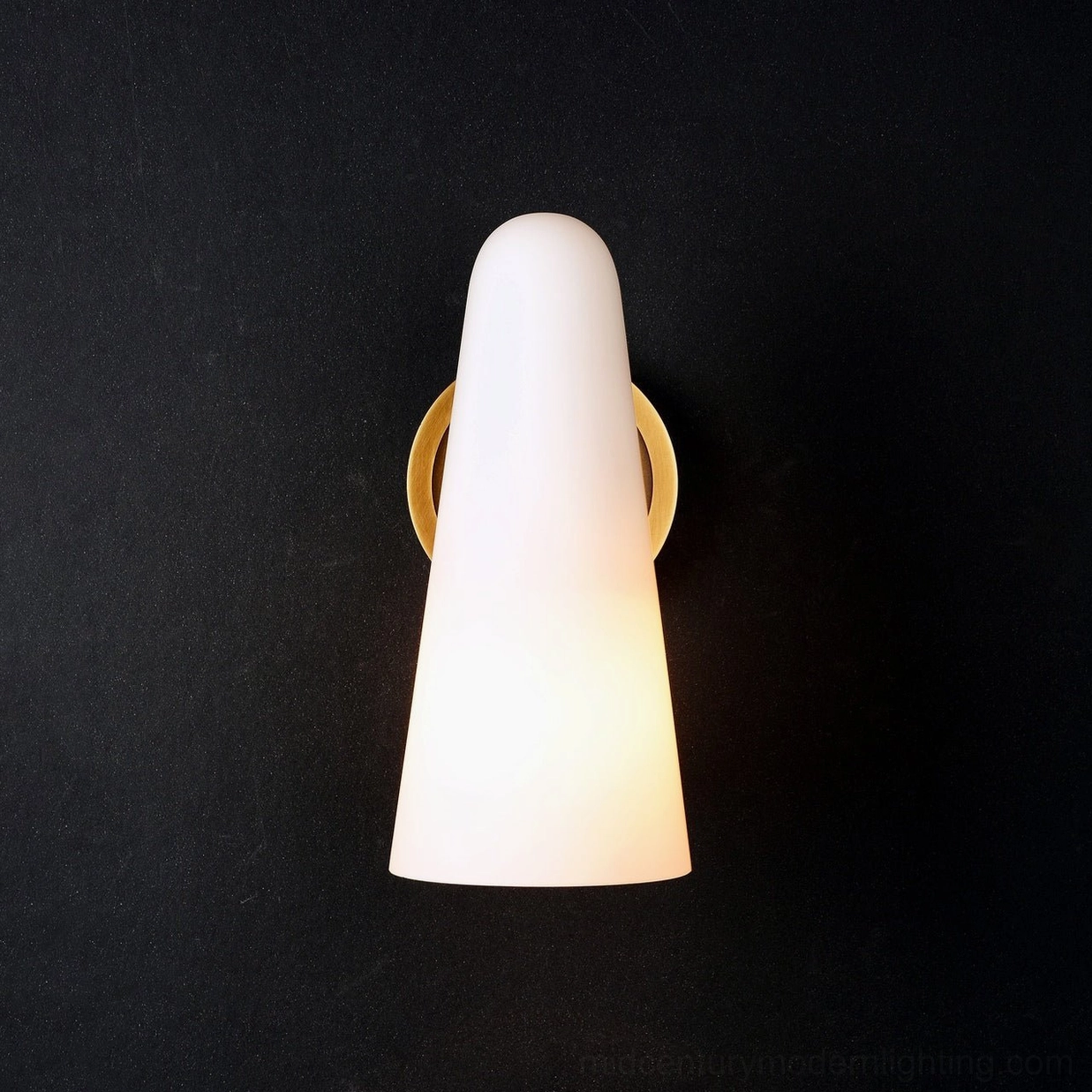 Single Montfaucon cone wall sconce with polished brass gold base on black wall background glowing warm light