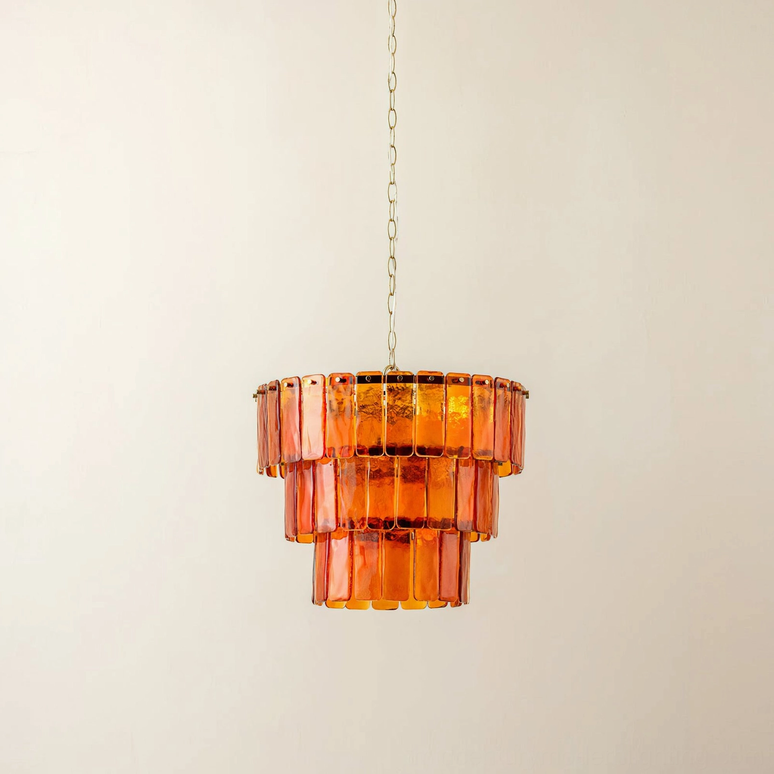 Moreland compact tiered glass pendant light with hanging chain in studio setting