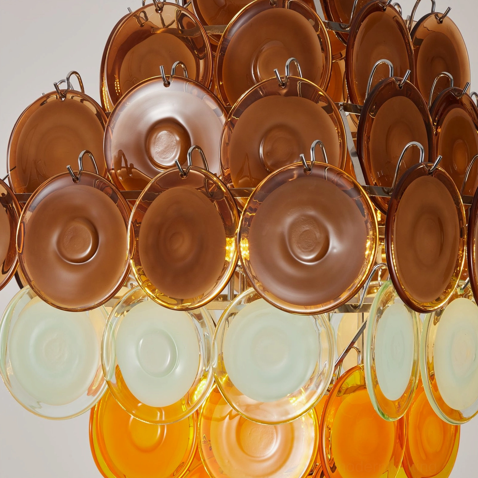 Close-up detail of Mortimer glass disc chandelier showing amber and mint glass assembly with metal mounting clips