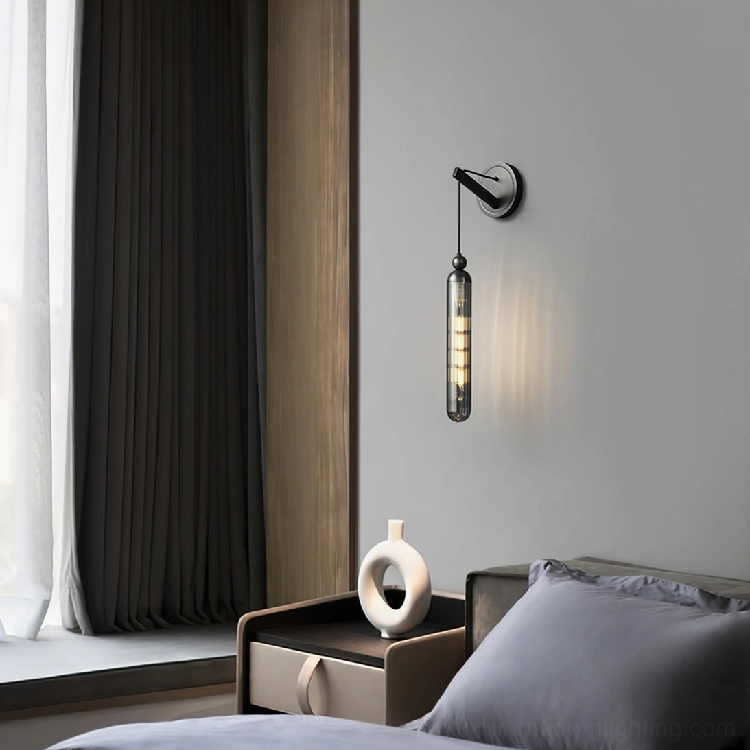 Matte black Mullan wall lamp with smoked cylindrical glass in contemporary bedroom setting
