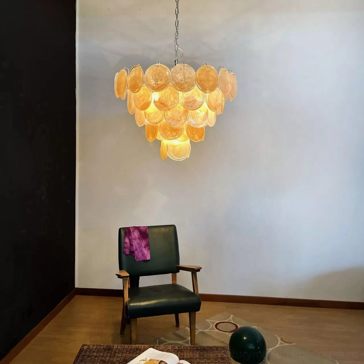 Vintage yellow Murano disc chandelier illuminated in minimalist residential sitting room with green armchair