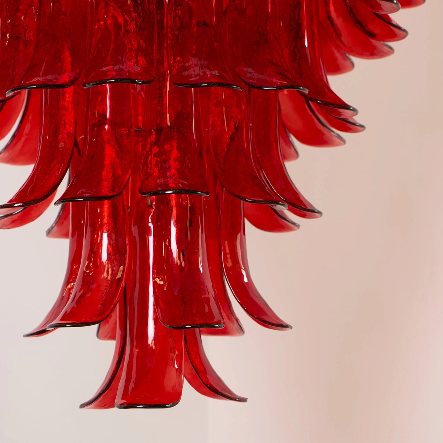 Close-up side view of hand-blown Murano glass chandelier showing curved downward-hanging red glass petals and gold metalwork