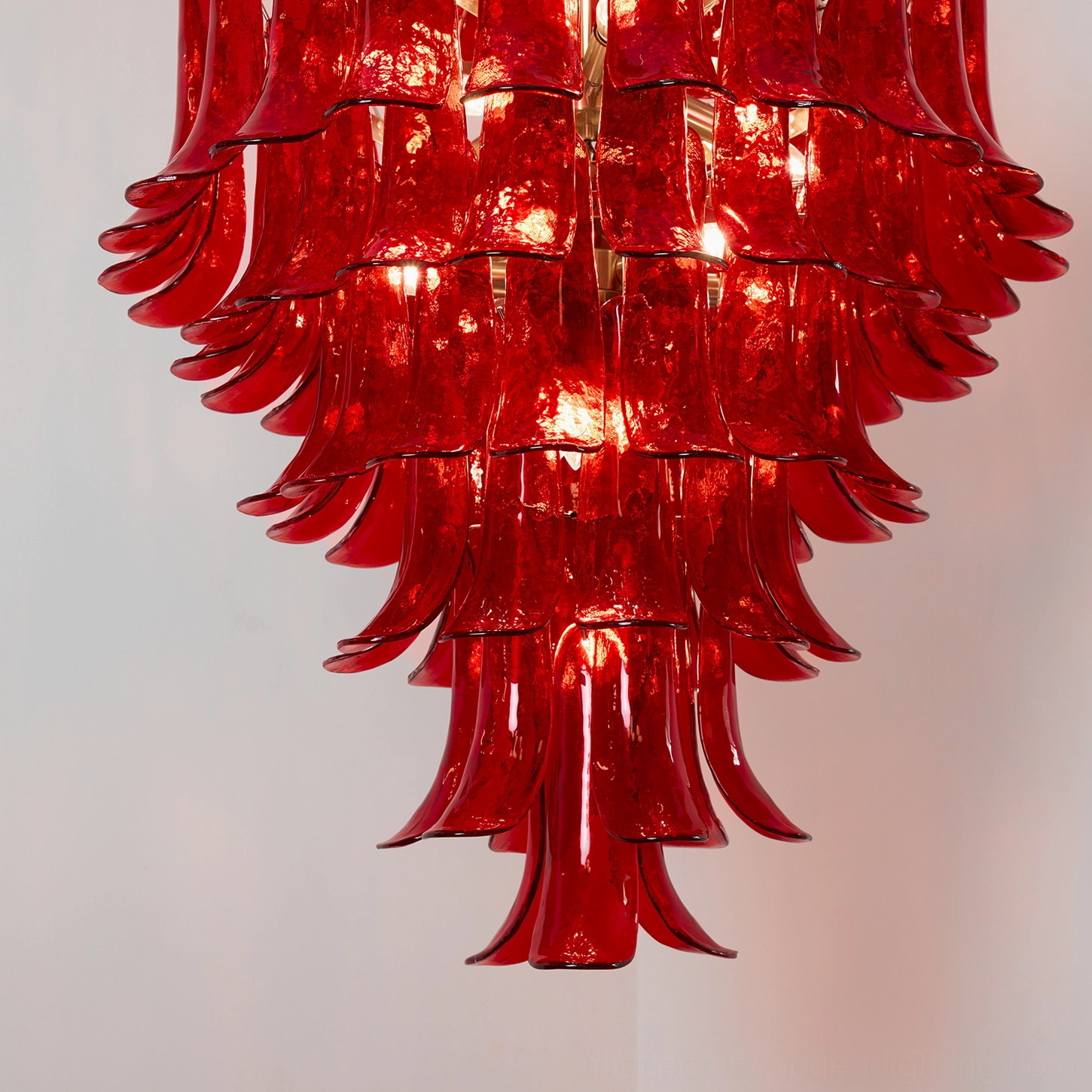 Symmetrical front view of Murano hand-blown glass chandelier with tiered petal design in translucent red and polished gold frame
