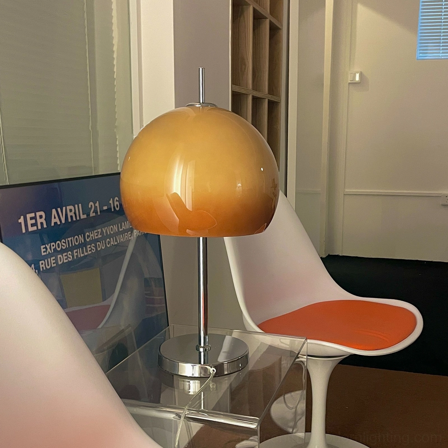 Mushroom lamp with chrome stand and amber acrylic dome in contemporary apartment setting