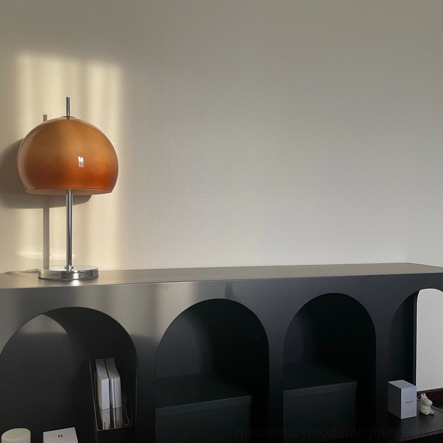 Mushroom table lamp detail shot showcasing amber gradient dome shade and polished chrome metal base construction