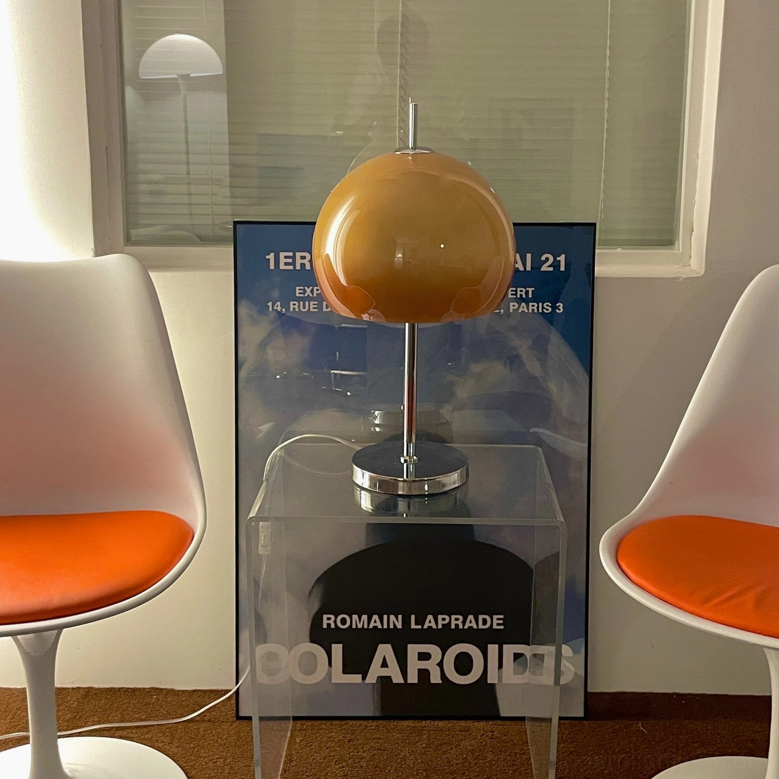 Mushroom table lamp with brown amber shade and chrome base in minimalist dining corner with poster wall