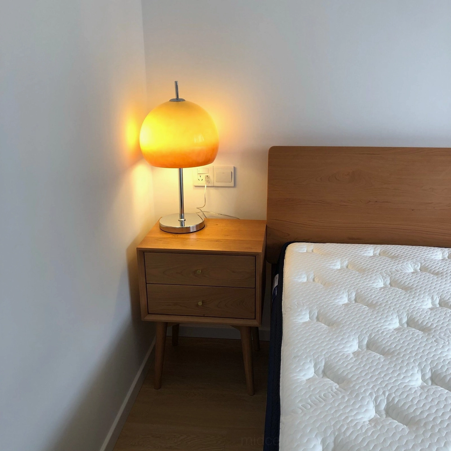 Vintage mushroom lamp with yellow gradient shade on wooden nightstand in contemporary bedroom corner