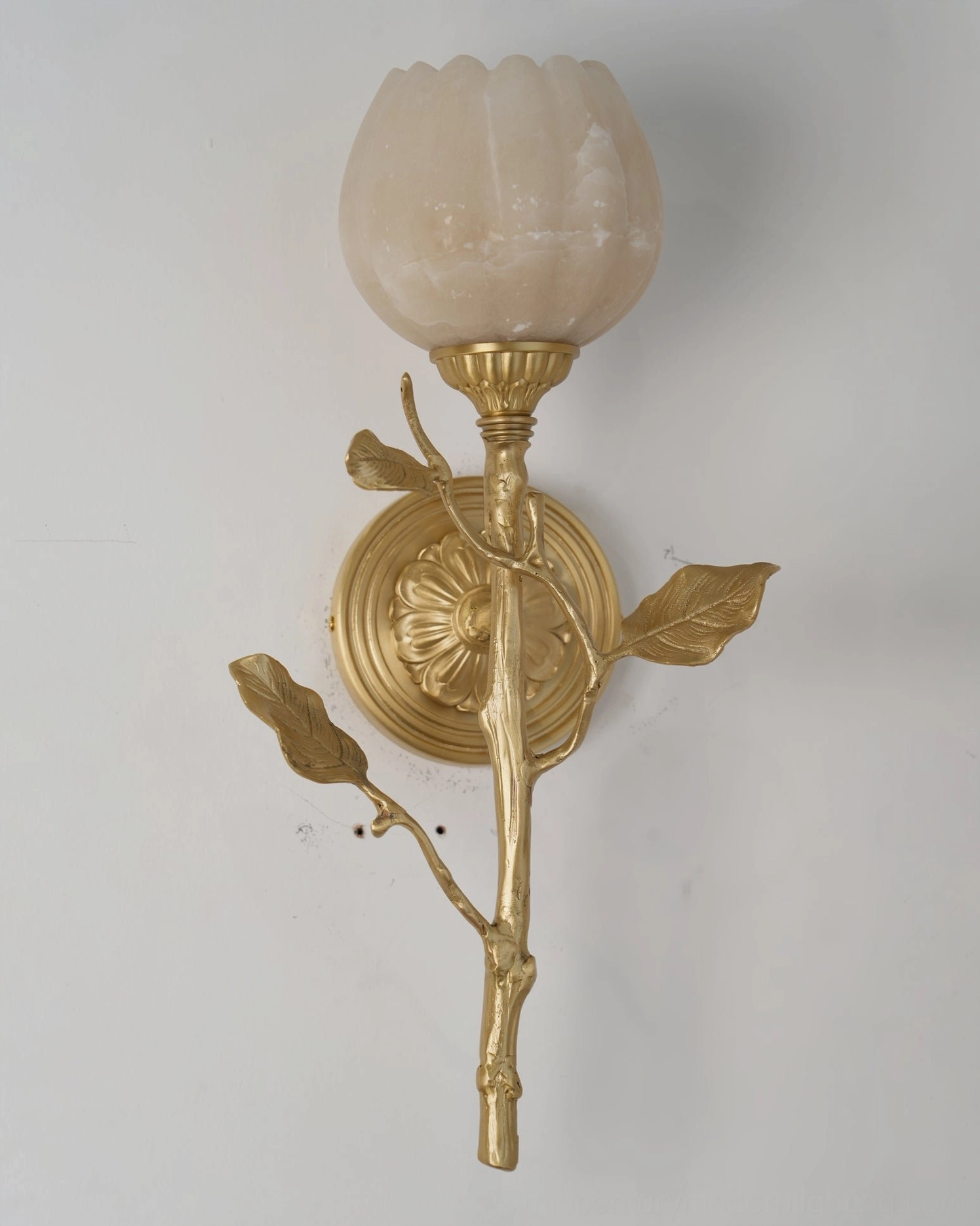 Natalia tulip-shaped alabaster wall sconce front view with carved brass backplate on white wall