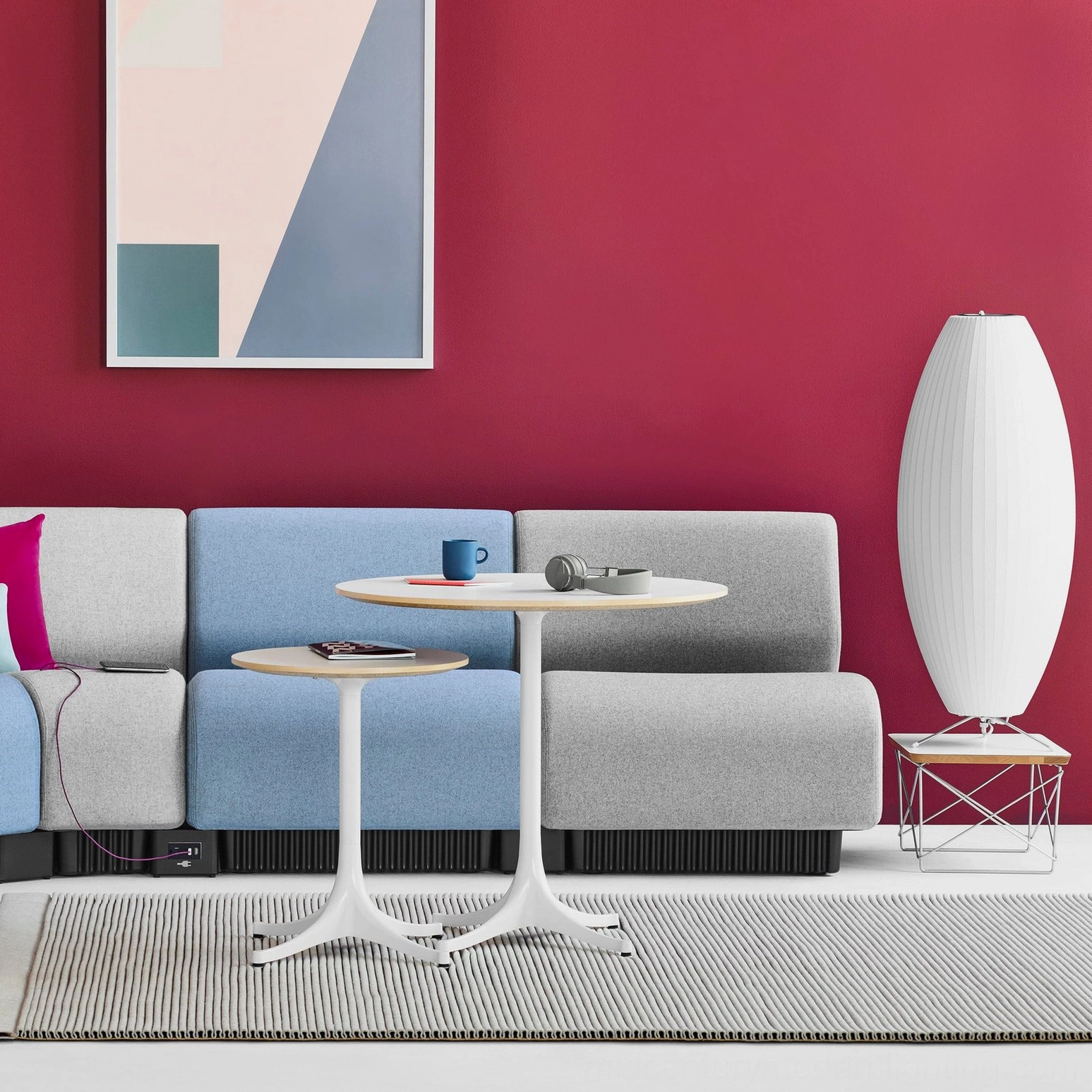 Tall cylindrical white George Nelson bubble lamp in modern minimalist cafe space with magenta accent wall and round side tables