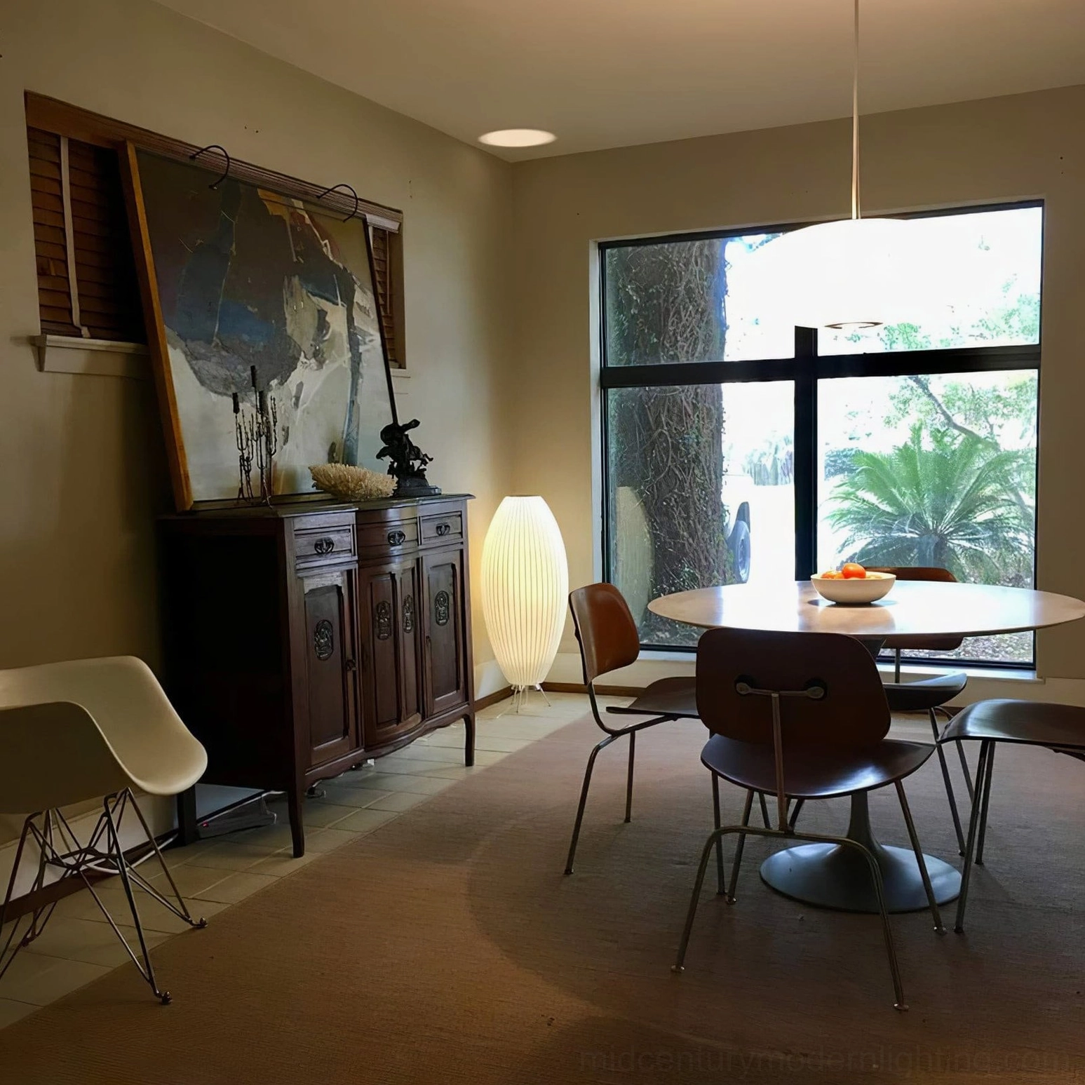 White George Nelson tripod table lamp creating warm glow in vintage mid-century modern dining room with natural wood furniture