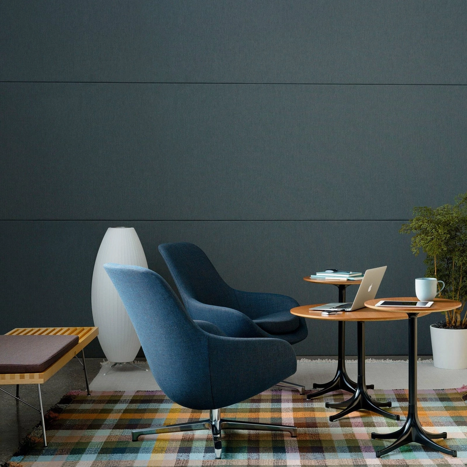 Tall white Nelson bubble lamp in contemporary corporate coworking lounge with navy accent chairs and plaid area rug