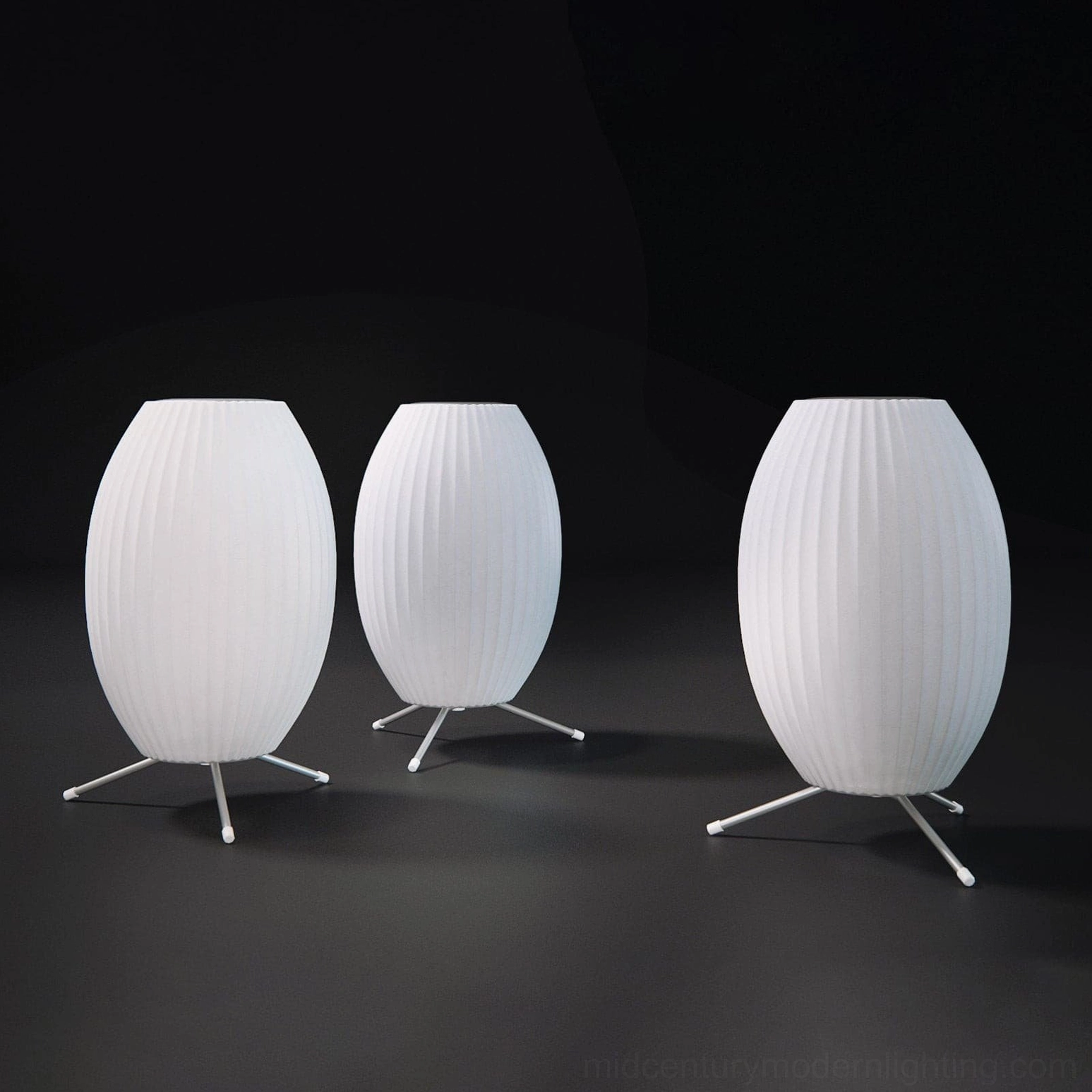 Group of three George Nelson bubble lamps with matching tripod bases in different sizes on dark grey studio background