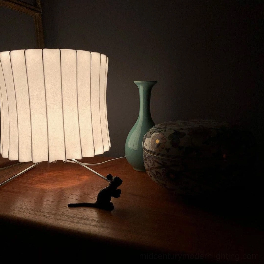 Close-up detail of cylindrical ribbed fabric Nelson bubble lamp on dark wood side table with vintage decorative accessories
