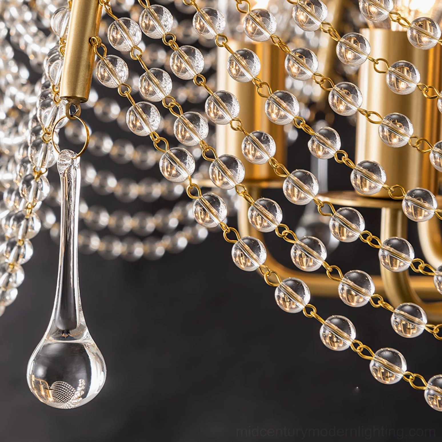 Detailed side view of Neville chandelier crystal bead strands and brass lamp arms with hanging glass accents