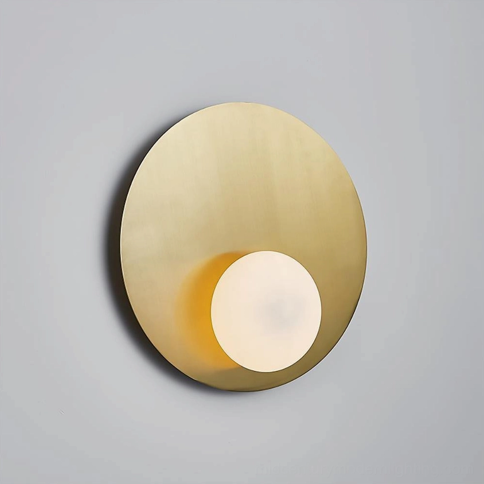 Nodes angled wall sconce three-quarter front view showing curved brass base and glowing frosted glass sphere