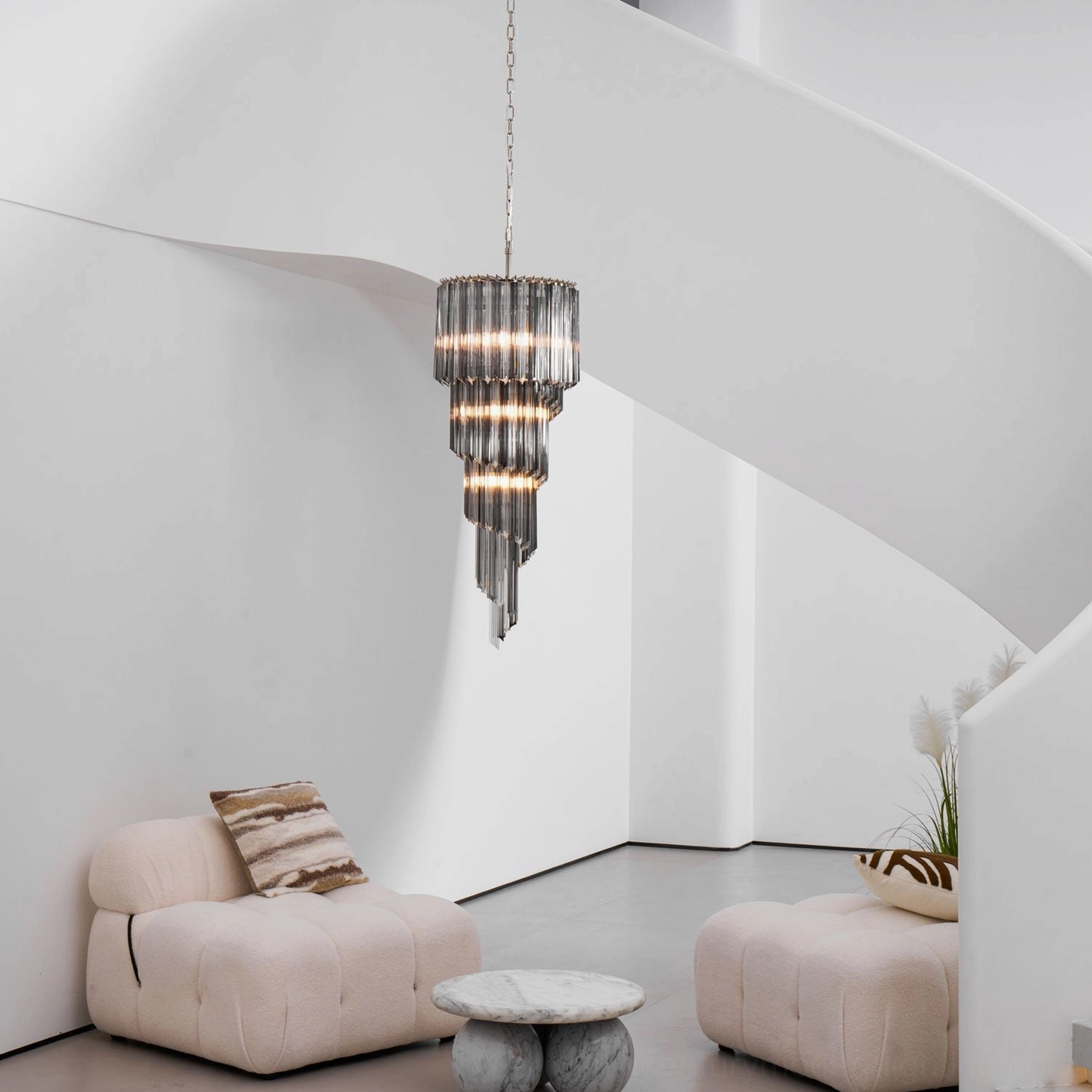 Noir spiral chandelier in minimalist white living room with patterned throw cushions, three-quarter view