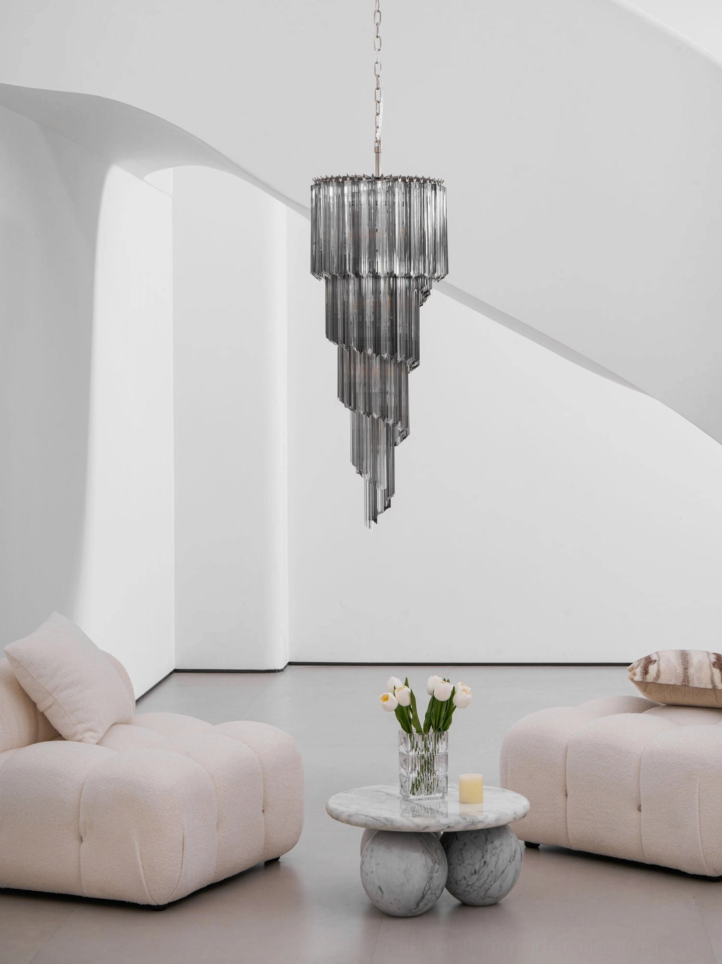 Smoke gray cascade chandelier in high-ceiling foyer, vertical architectural lighting statement