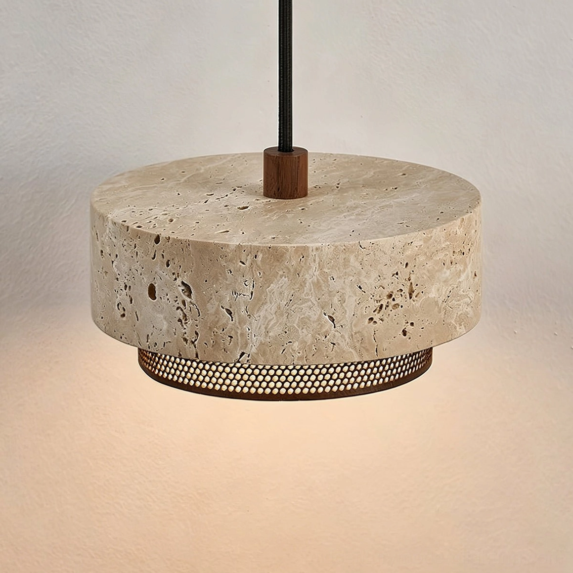 Nolan travertine pendant light photographed from below, revealing unfinished stone bottom surface and internal light structure with perforated rings