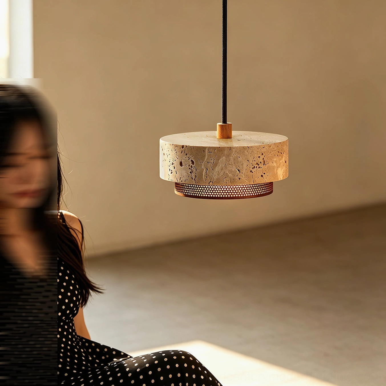 Nolan travertine pendant light installed in warm minimalist living space above side table, creating organic modern ambiance