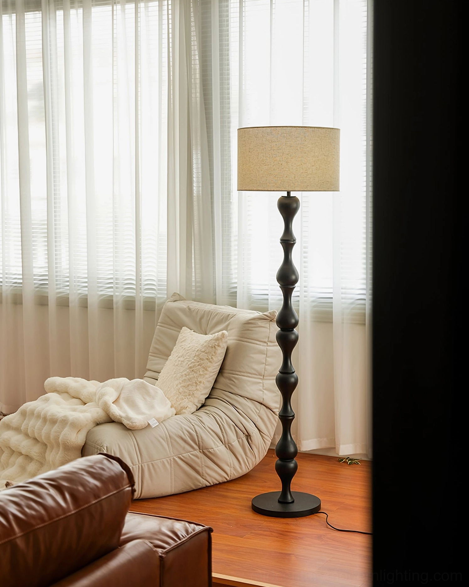 Scandinavian floor lamp Norden in black, positioned in contemporary living room with leather seating