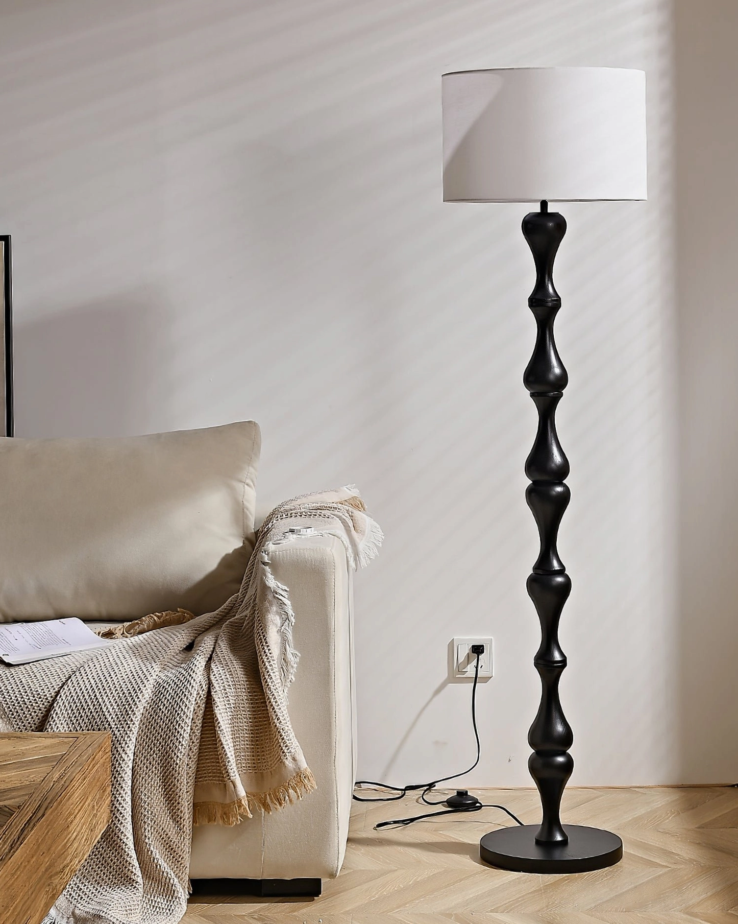 Black Norden floor lamp with white shade in modern minimalist living room beside draped sofa