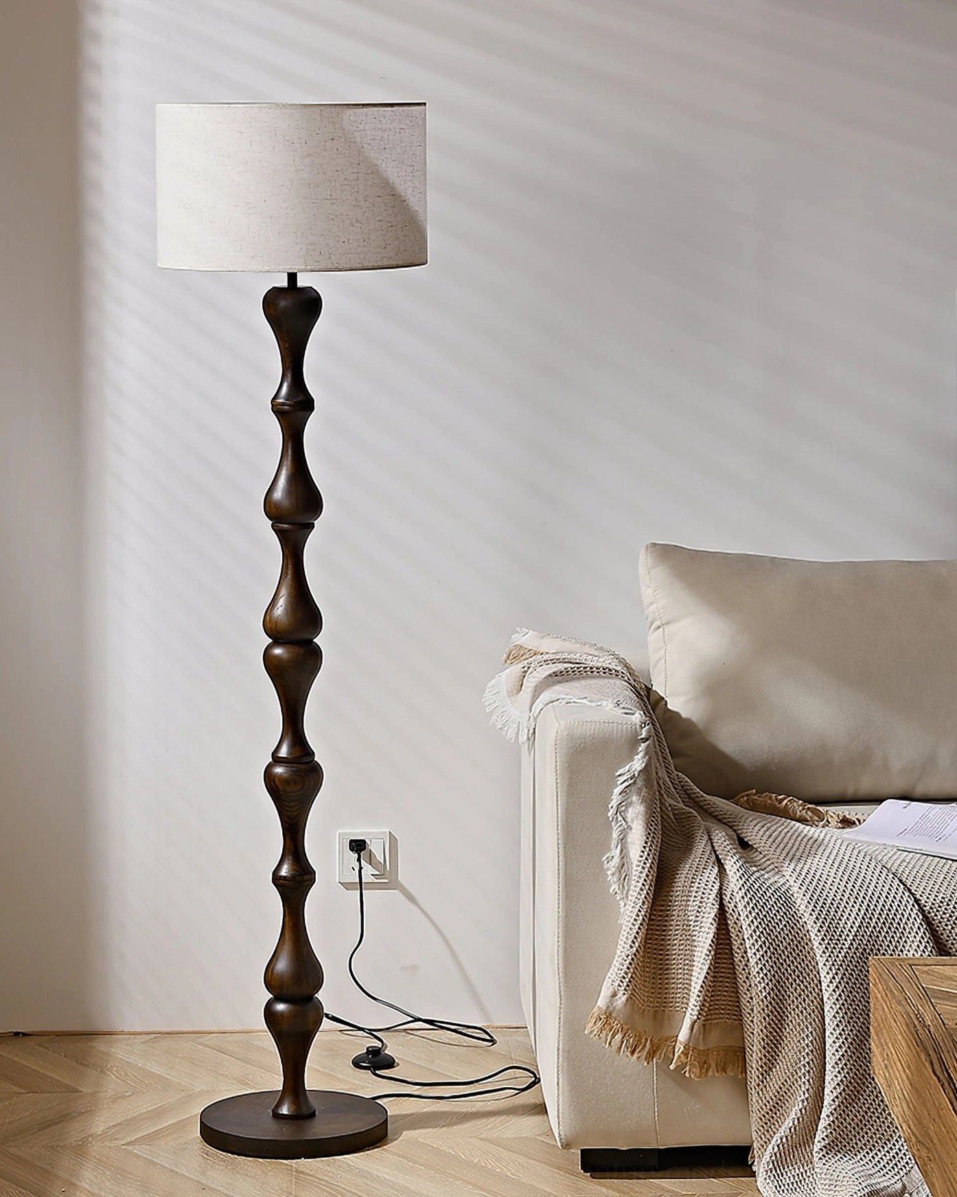 Unlit dark brown Norden sculptured floor lamp on herringbone wood floor with fabric sofa, minimalist retro