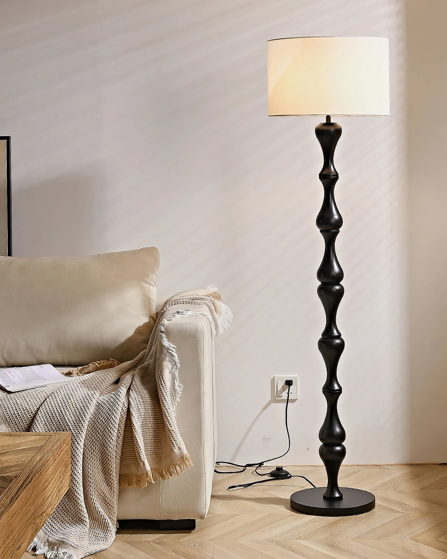 Illuminated Norden carved wood floor lamp in dark brown, creating warm vintage ambiance in cozy living space