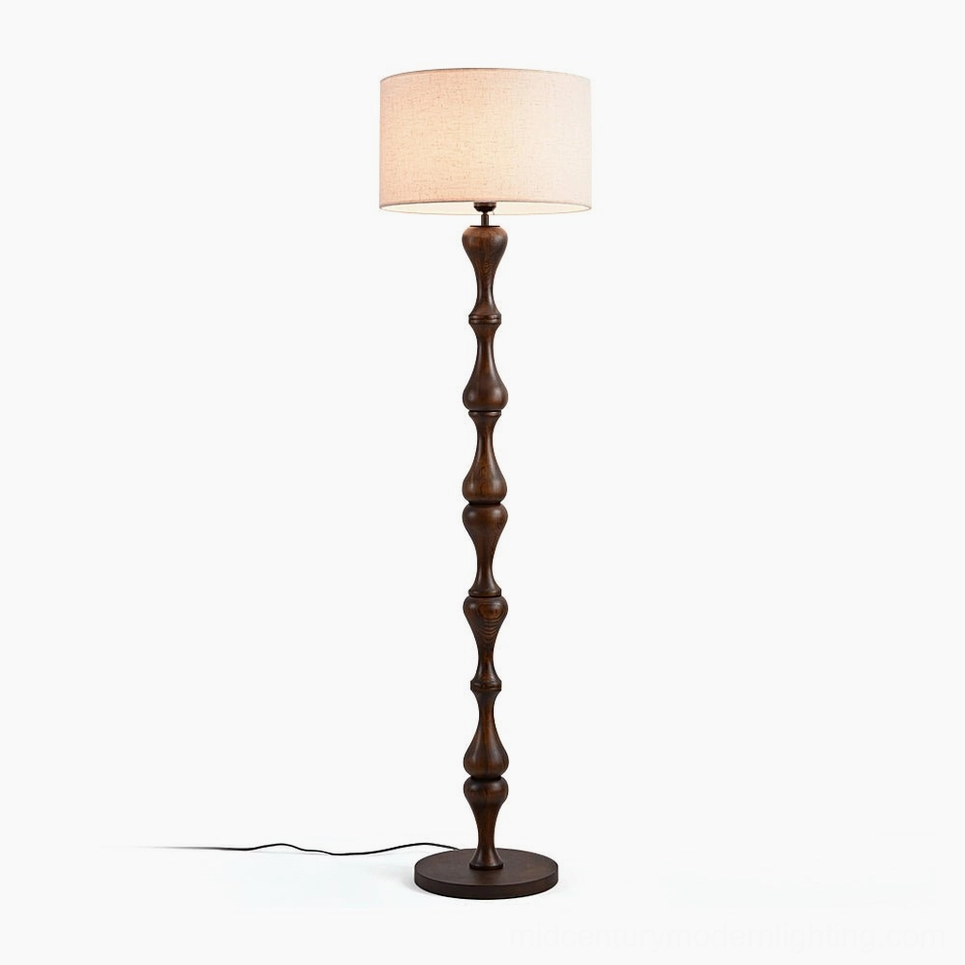 Norden carved wood floor lamp with walnut finish and beige fabric shade, frontal studio view