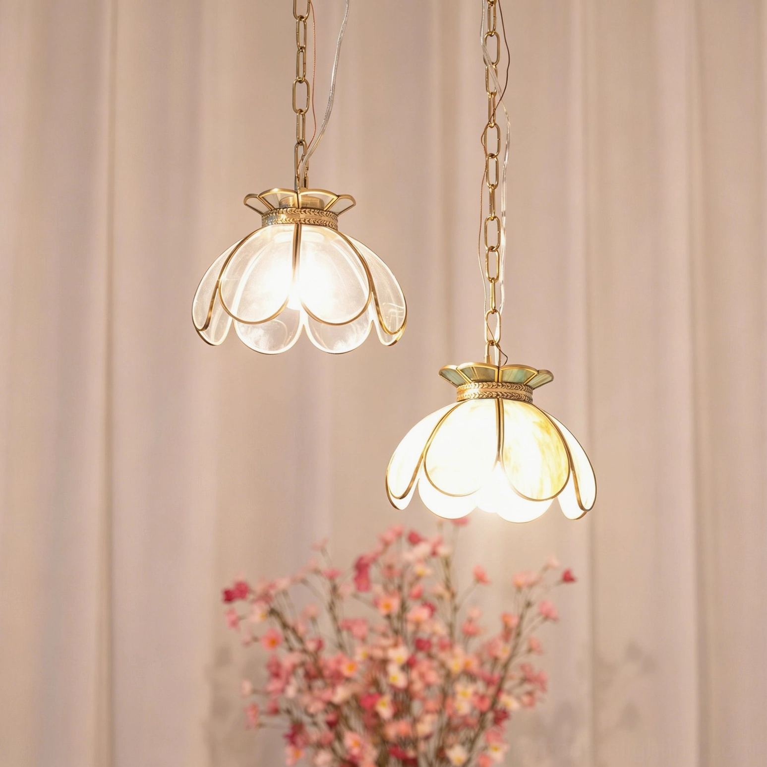 Two Odette pendant lights glowing warmly with pink floral background, low angle perspective showing vintage bohemian style