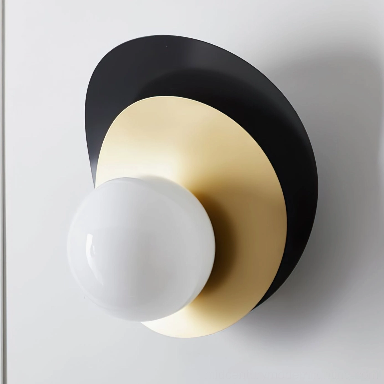 Asymmetrical dual-disc design of Olivia wall sconce with brass and black finish holding large spherical glass bulb
