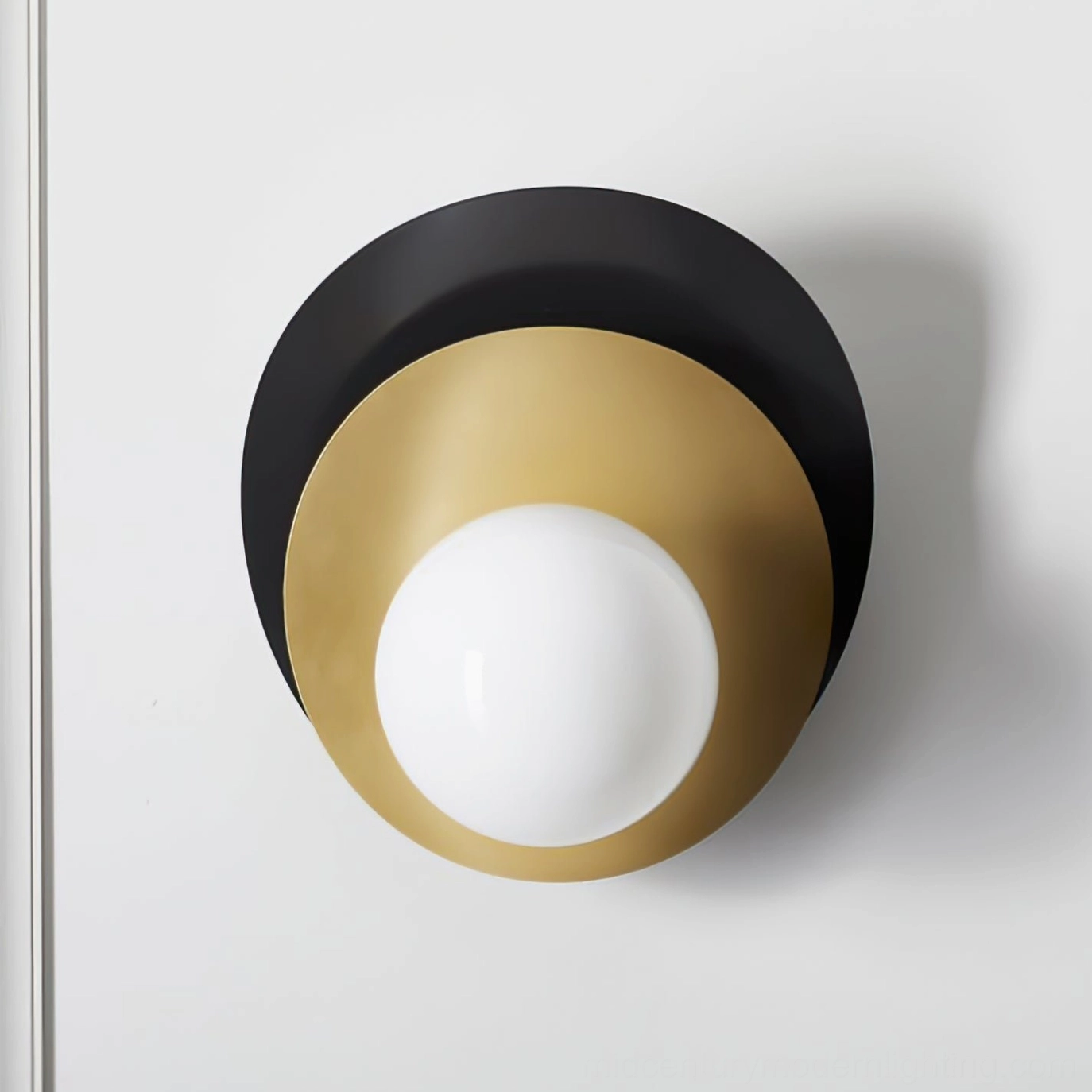 Olivia wall sconce showcasing large frosted glass globe with black and brass layered disc design on neutral background