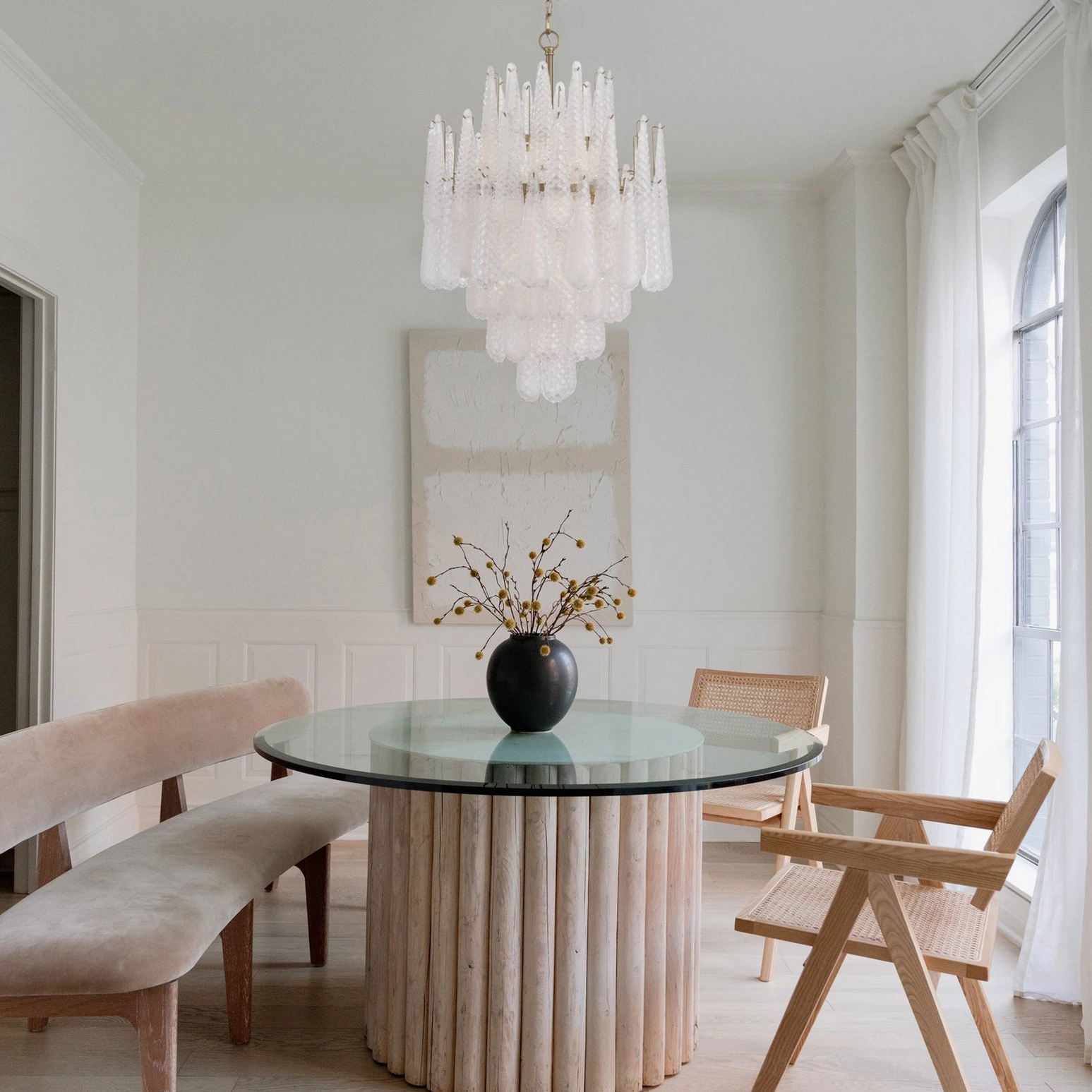 Ollie frosted teardrop chandelier installed in modern minimalist dining room with white walls and wooden table