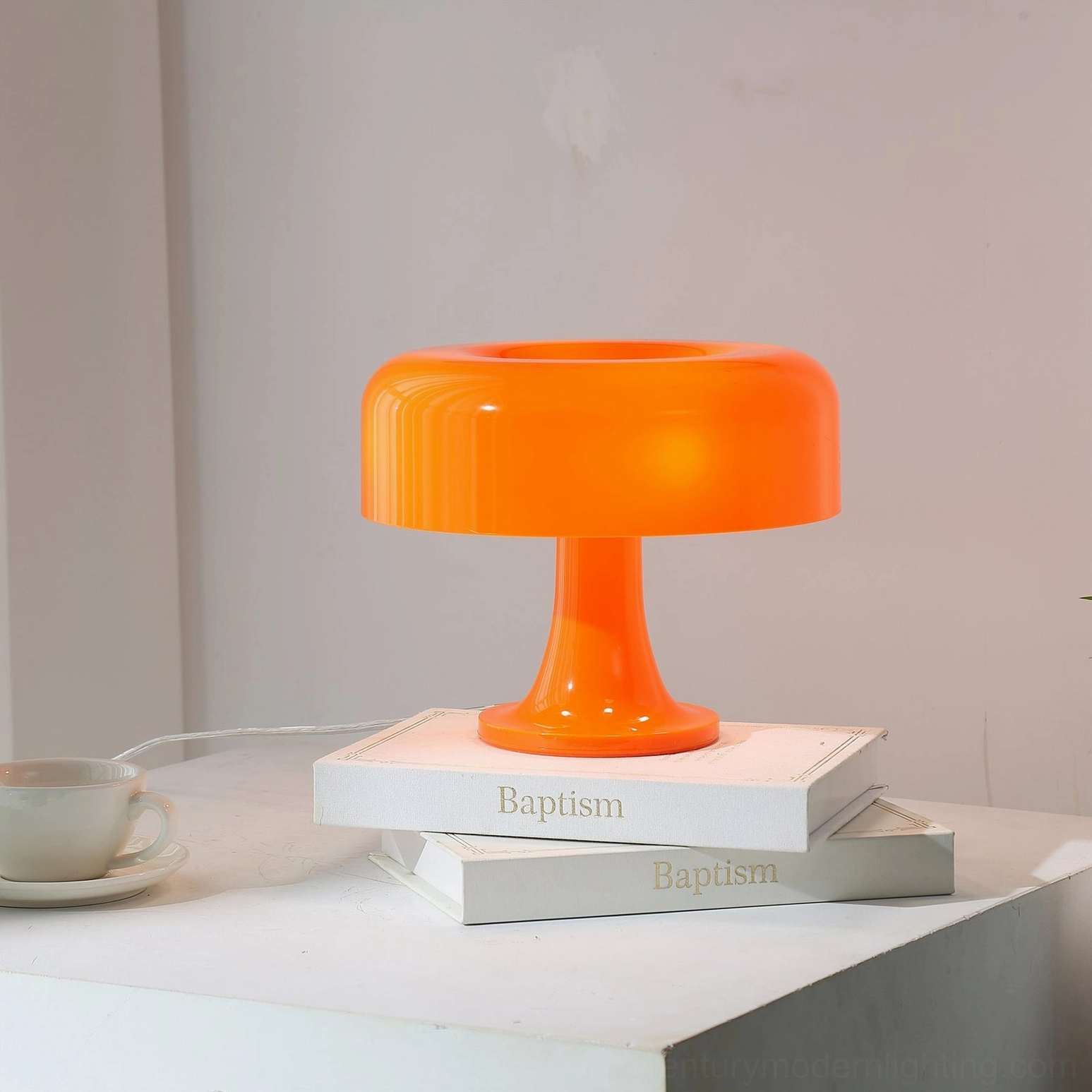 Orange mushroom table lamp front side view on clean white tabletop with minimalist coffee cup and decor