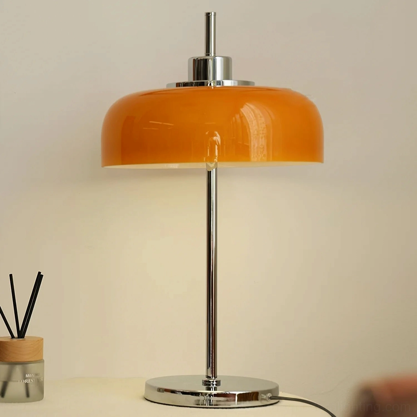 Modern home orange table lamp on living room side table styled with stacked books and dried flower vase