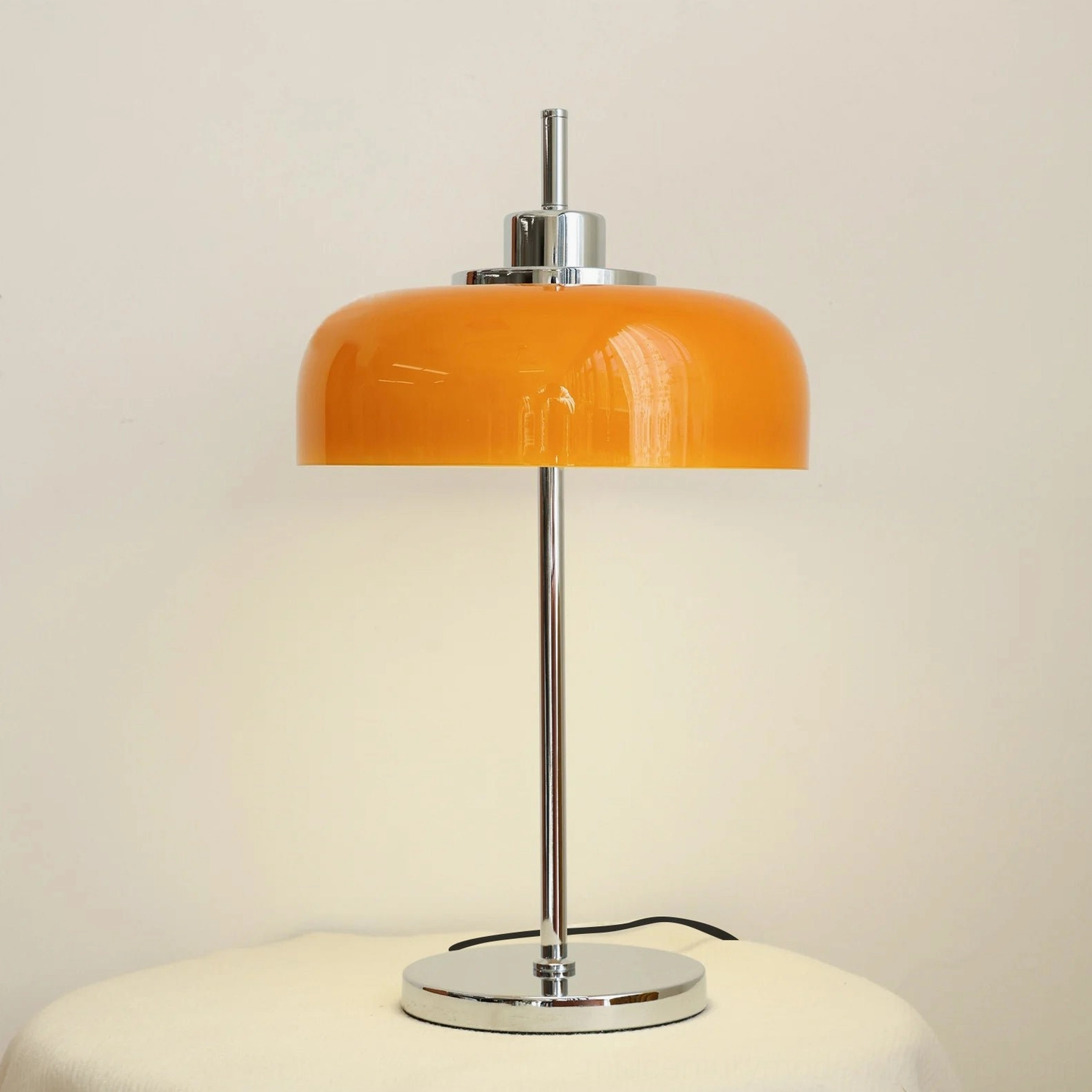 Burnt orange retro table lamp on off-white side table against warm-toned wall - direct front view