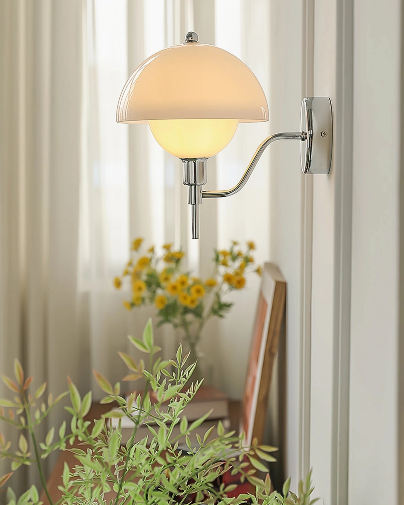 Warm ambient lighting from chrome anchored orb wall lamp in cozy home corner with plants and decorative elements