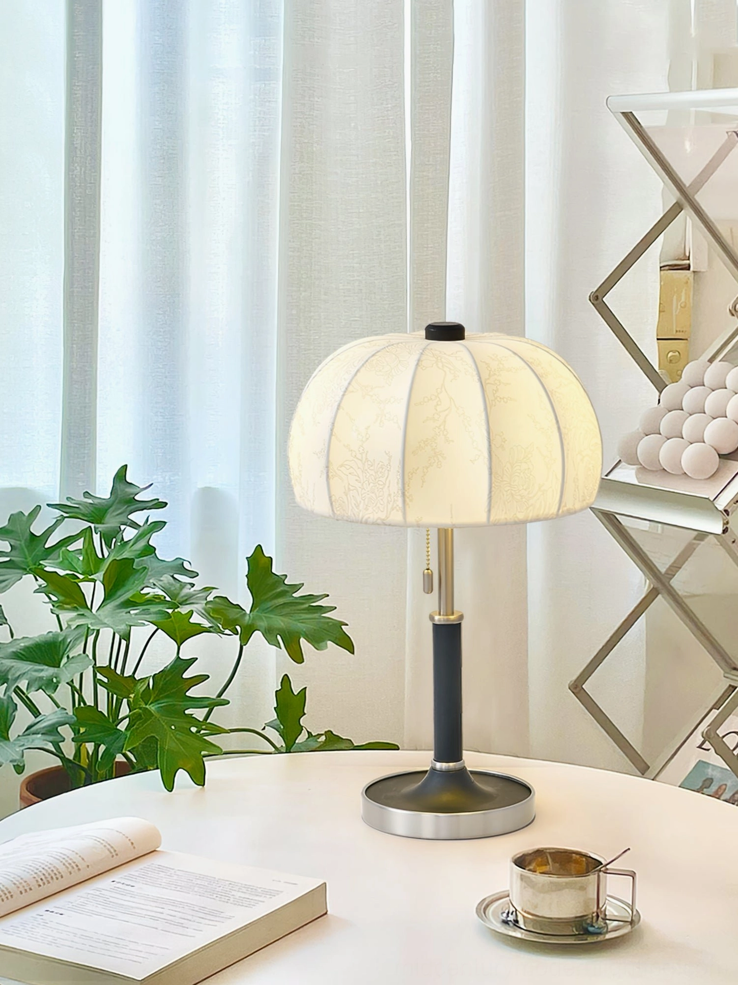 Black pole fabric table lamp with silver base on round dining table with books and coffee set