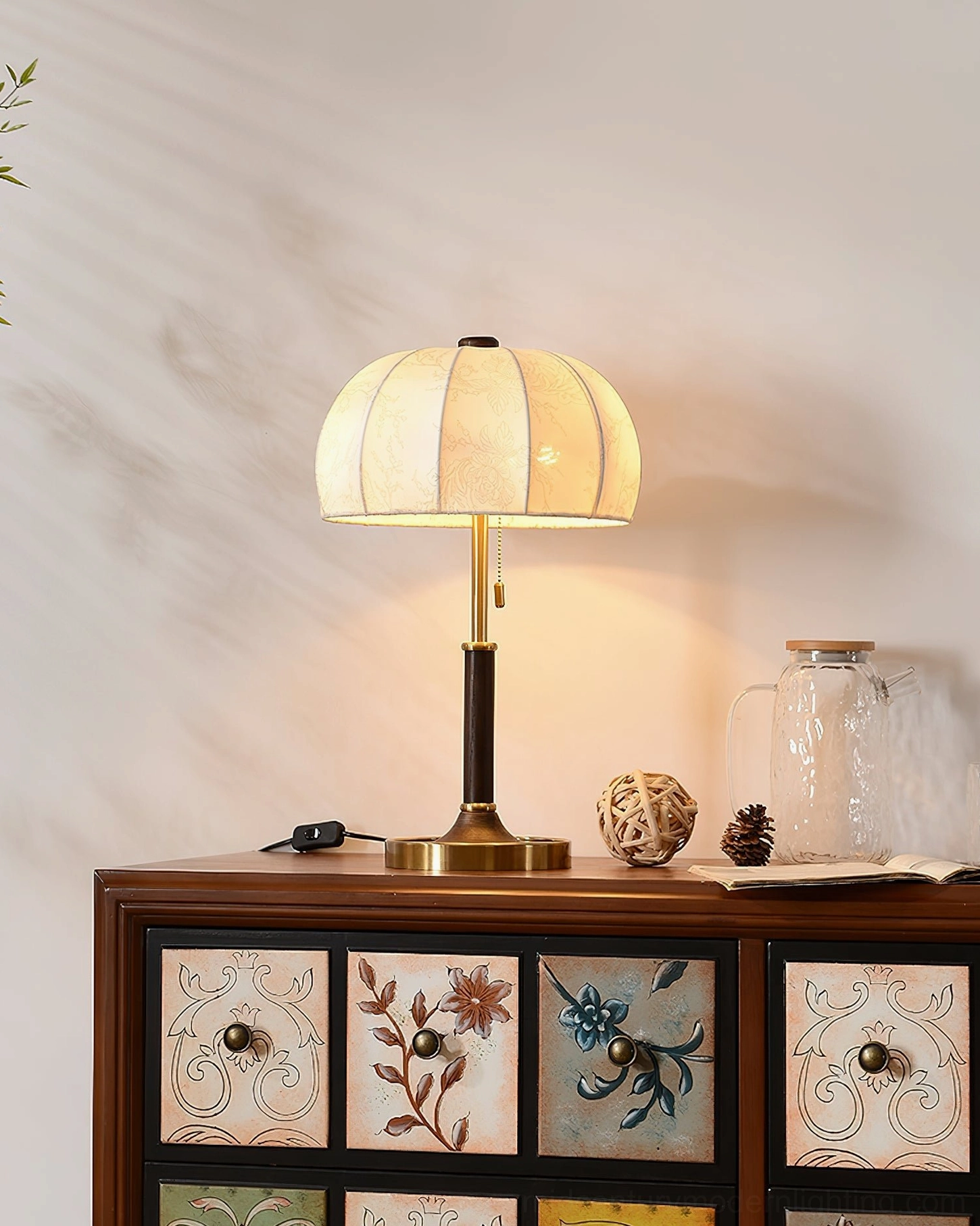 Lit fabric table lamp in American vintage home style with retro patterned drawer cabinet and ornaments
