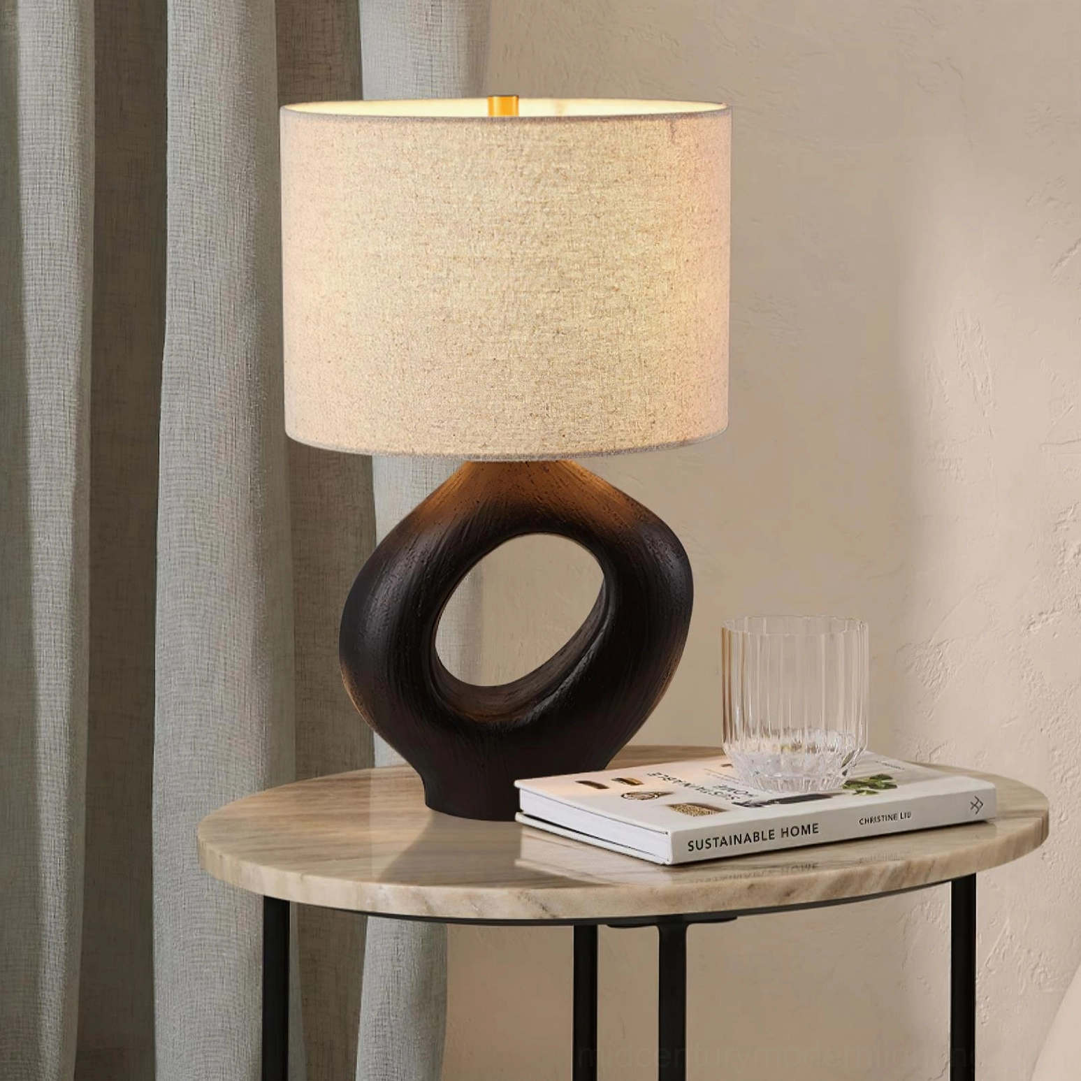Modern table lamp with organic sculptural form, warm ceramic base creating shadow play and ambient lighting