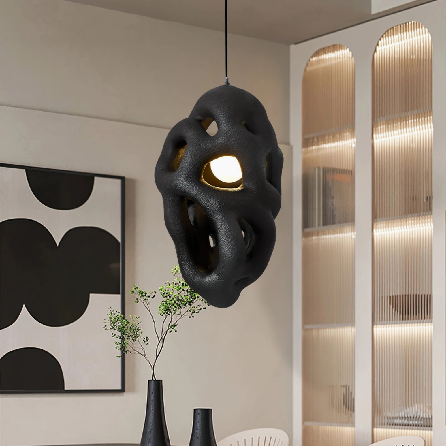 Black organic nest pendant lamp hanging in modern dining space with wall art, matte wabi-sabi style fixture