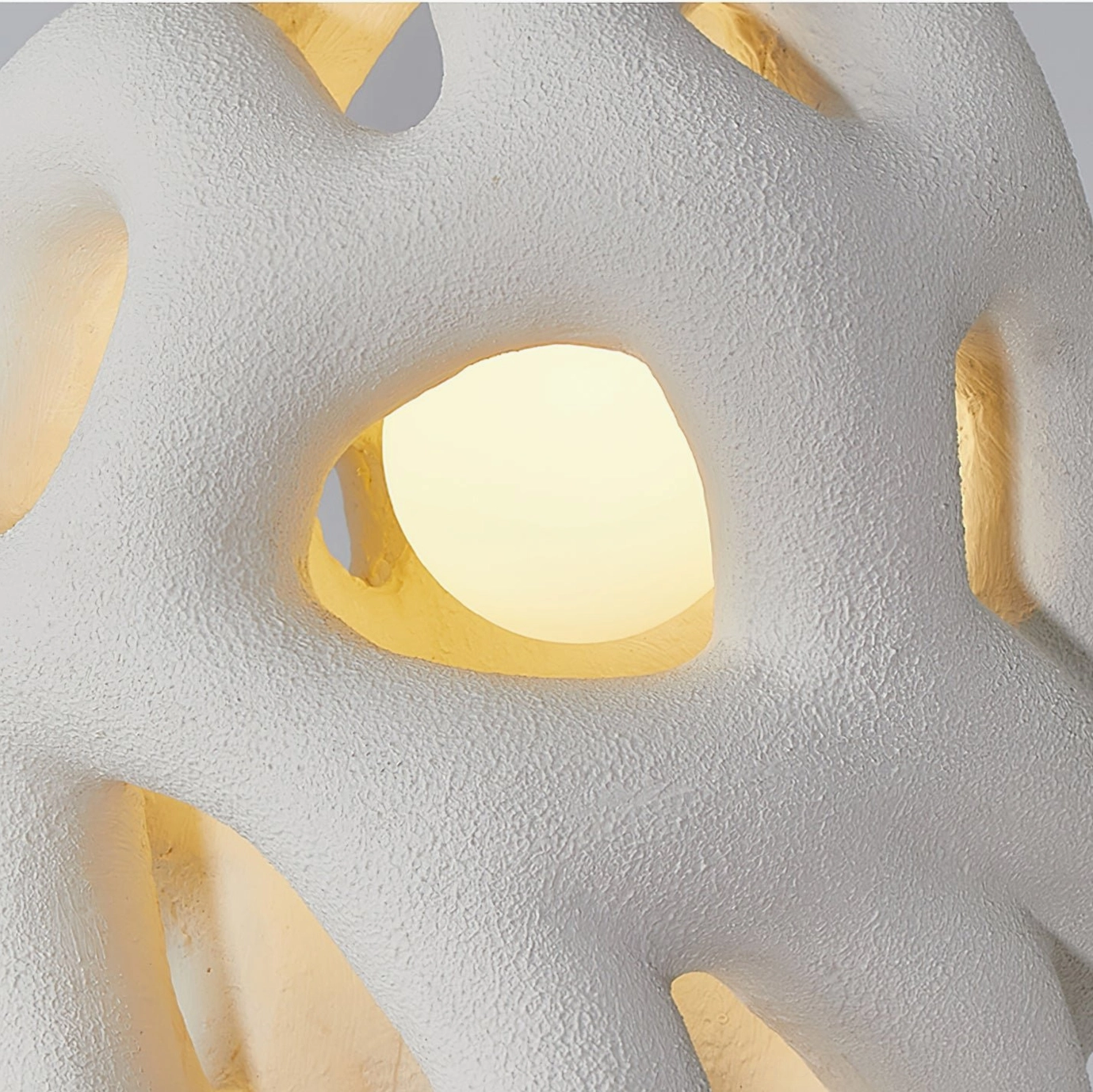 Macro detail of organic nest pendant lamp with glowing interior, sand-like rough surface texture illuminated