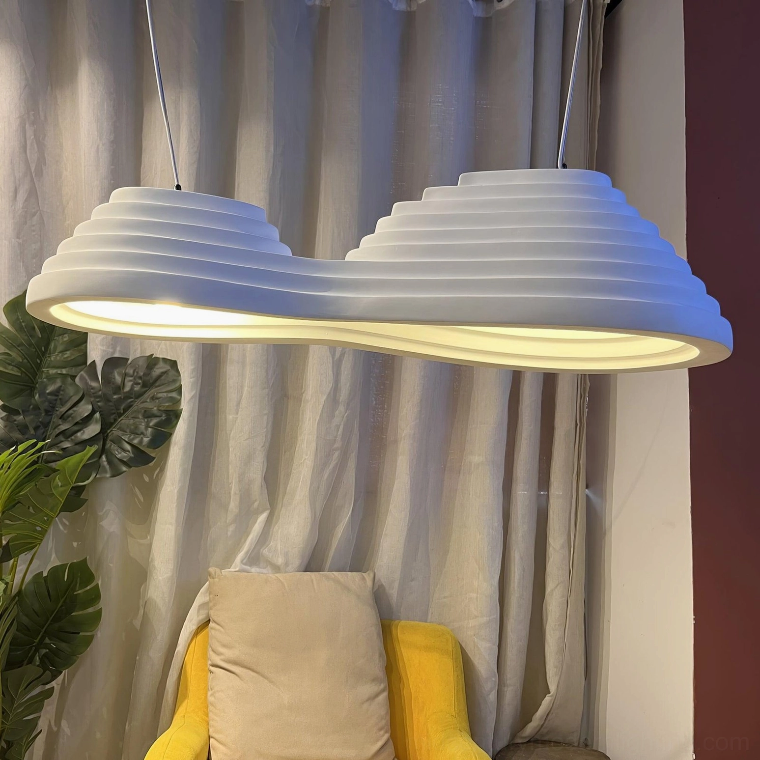 Layered pendant light suspended in cozy living lounge area creating warm ambient blue-toned glow