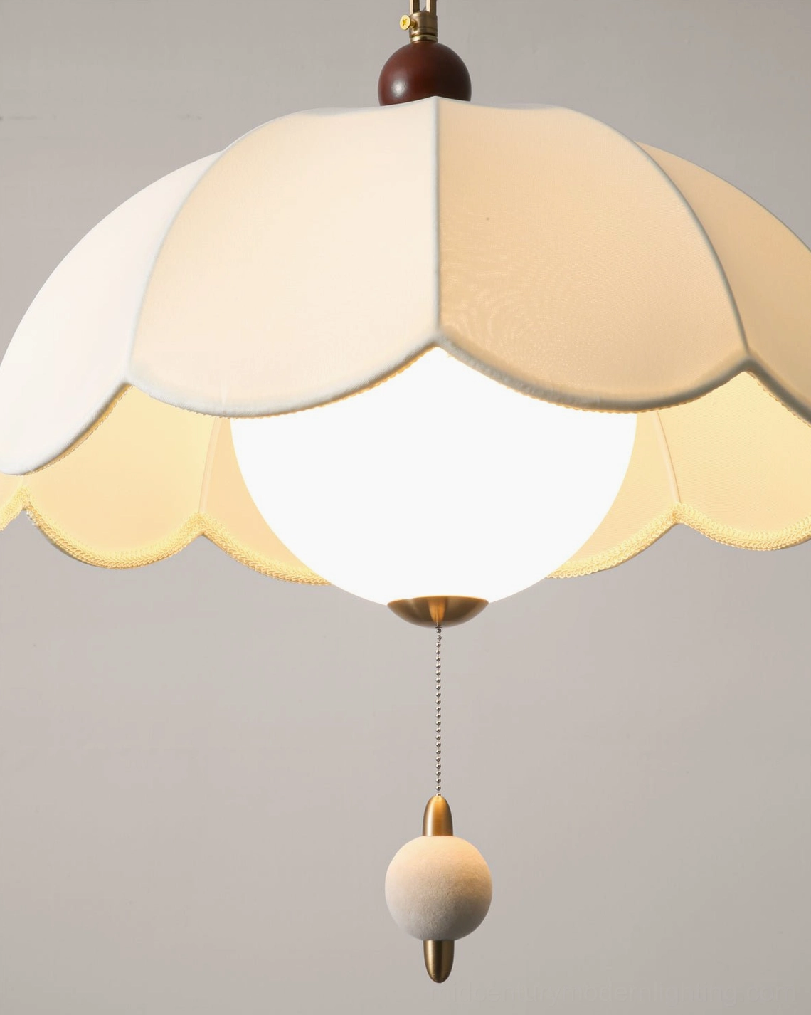 Close-up of Oriente pendant light showing layered scalloped fabric shade and glass bulb construction