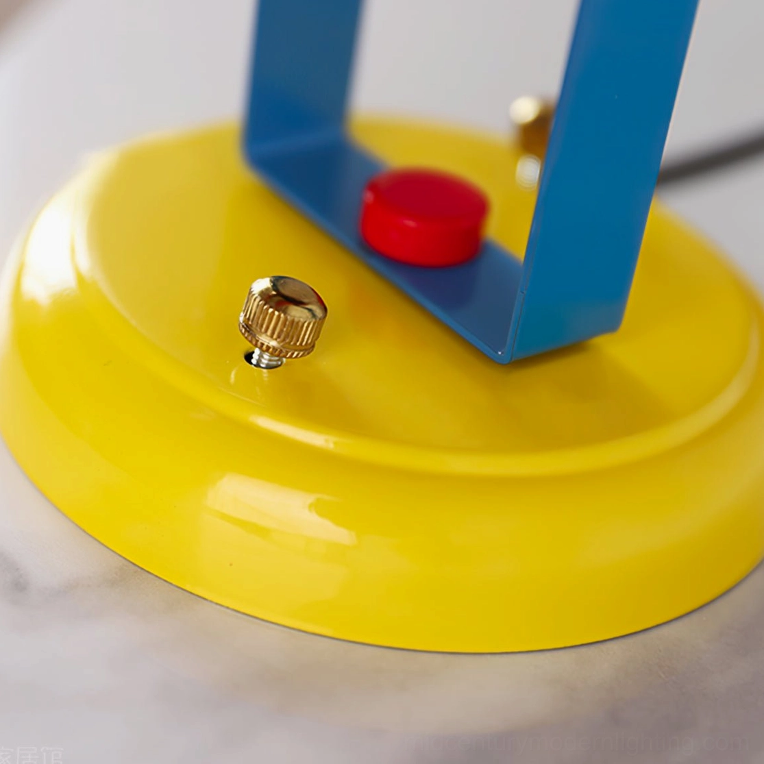 Orno wall lamp hardware components top close-up detail showing yellow metal base blue bracket brass screw and red adjustment knob