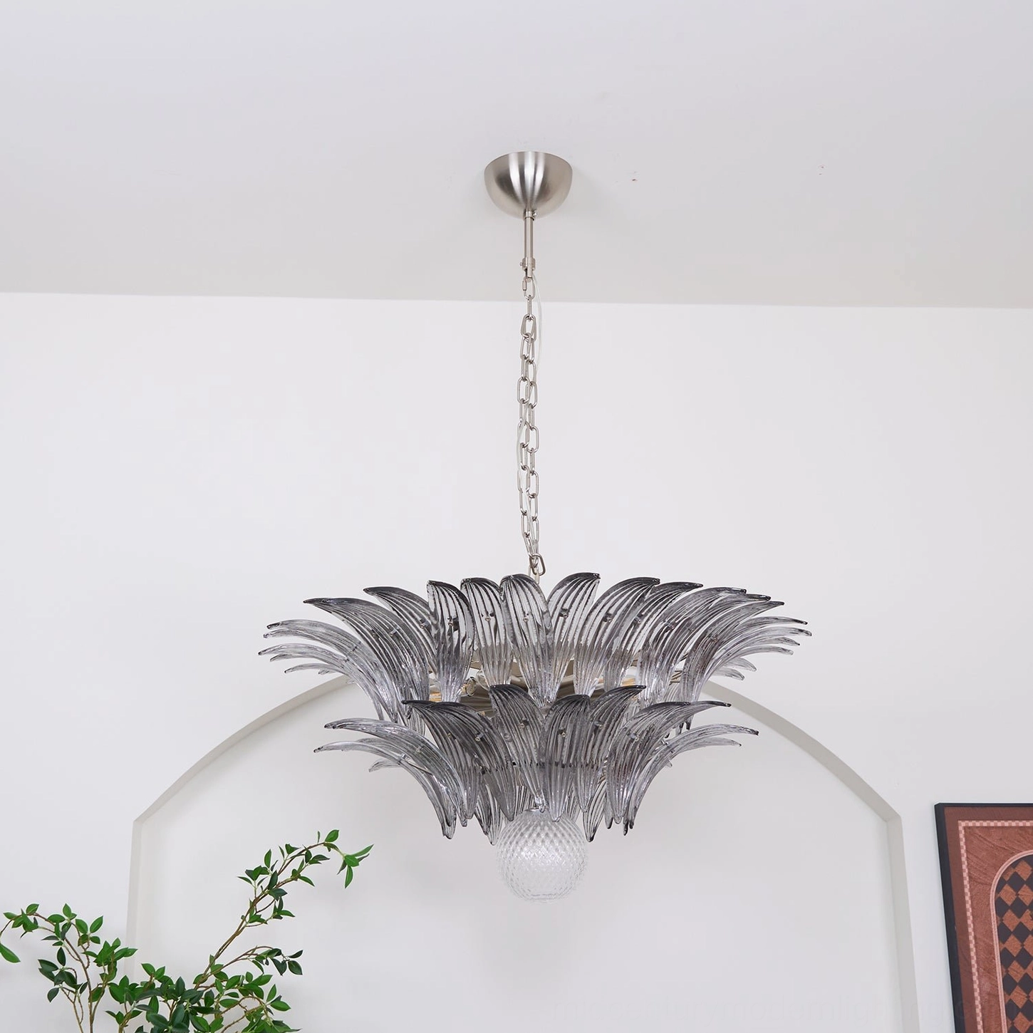 Front view of Palazzo Ball Chandelier with silver hardware and textured glass base orb against minimalist wall background