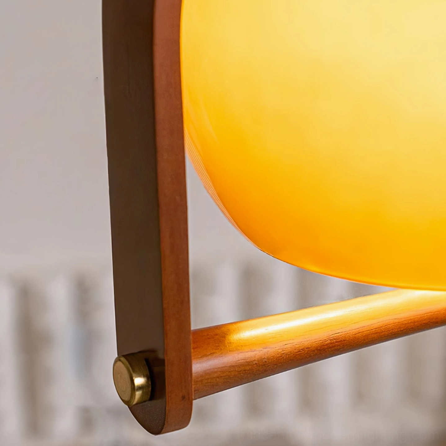 Pallade lamp translucent amber glass shade with brass fasteners and solid wood support rod close-up