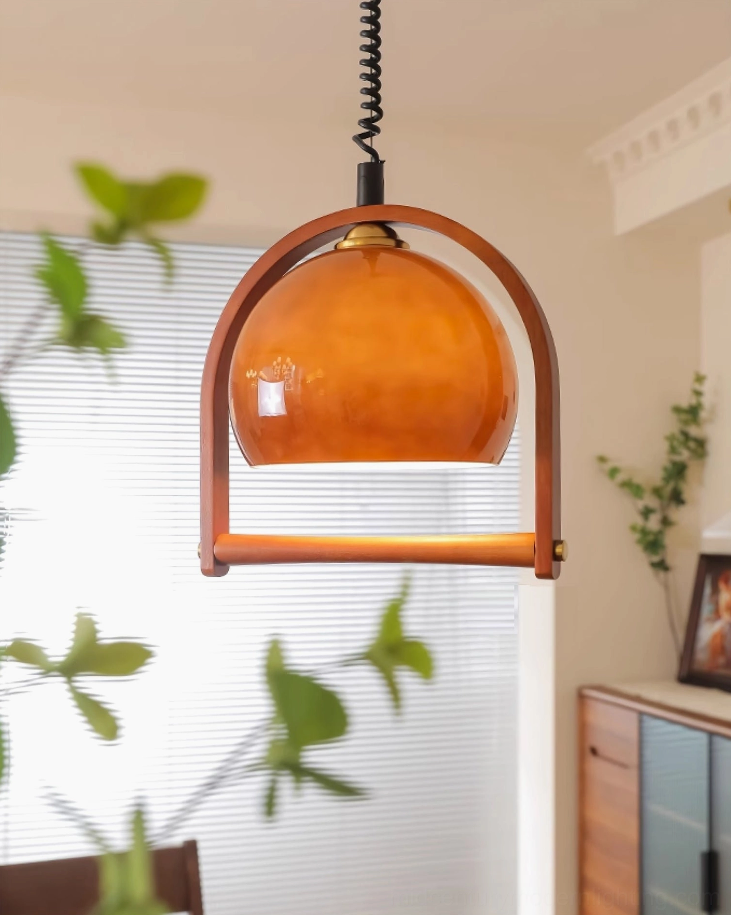 Pallade mid-century pendant light side angle view in modern living room with plants and window