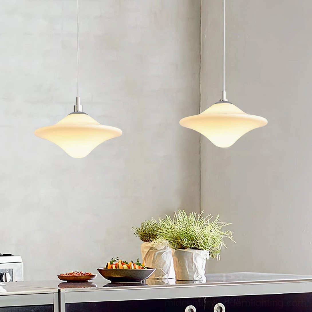Two pendant lamps over kitchen counter creating warm workspace lighting with potted plant decor