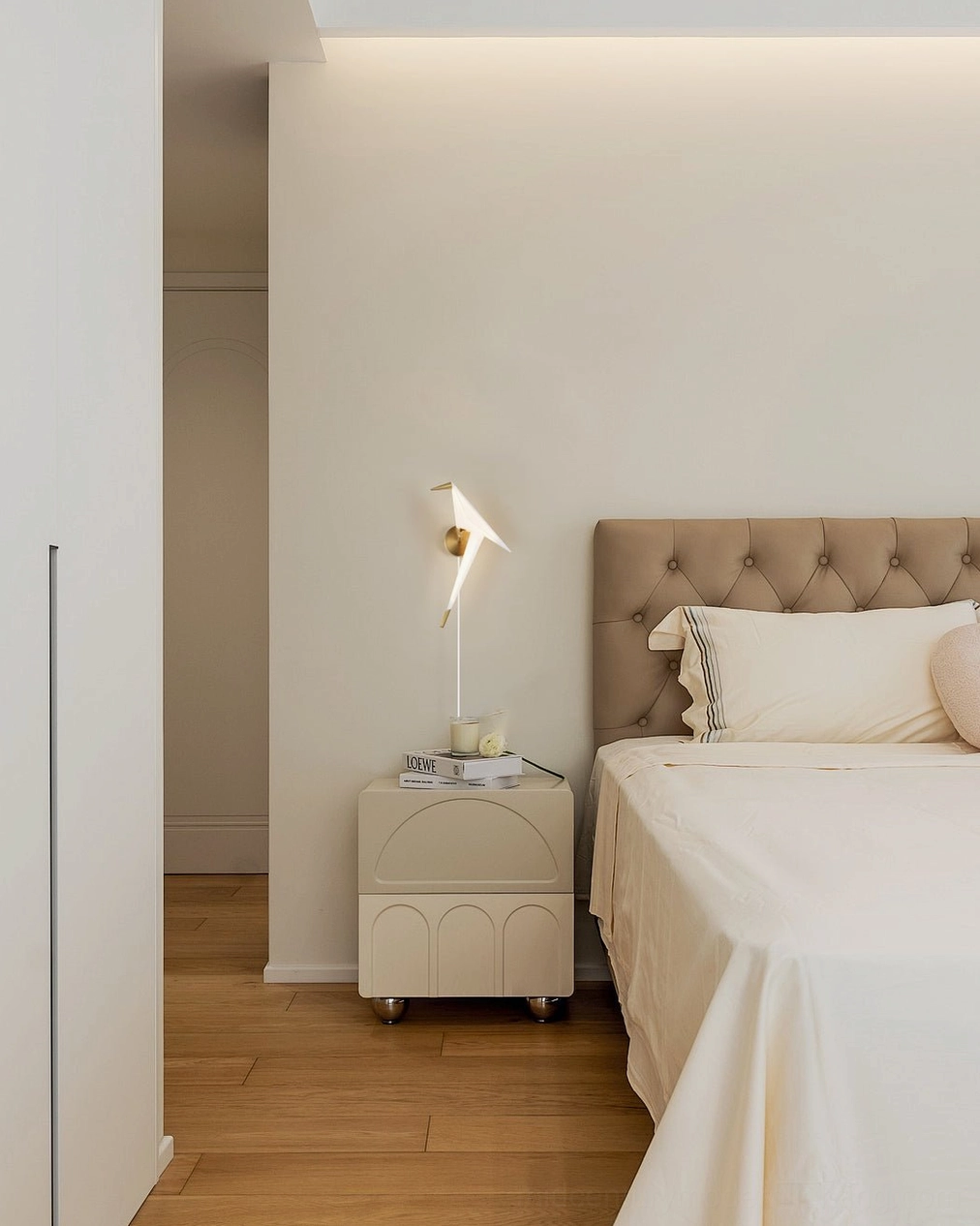 Perching Bird wall lamp above tufted headboard bed in cozy minimalist bedroom interior design setting